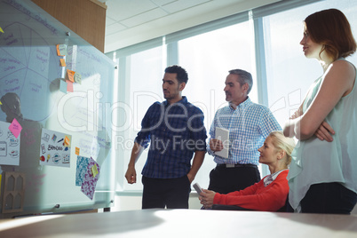 Thoughtful business colleagues looking at whiteboard in office