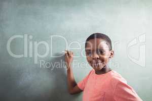 Portrait of boy standing by chalkboard