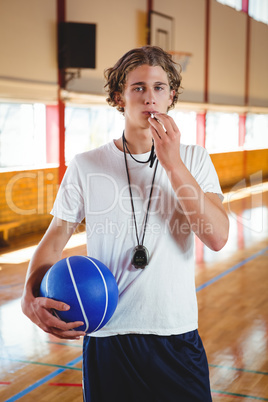 Portrait of male basketball coach with whistle and ball