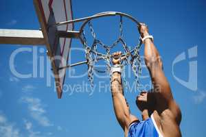 Close up of teenage boy hanging on basketball hoop