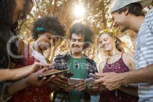 Happy friends using mobile phones together at campsite