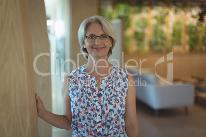 Portrait of smiling businesswoman by wall