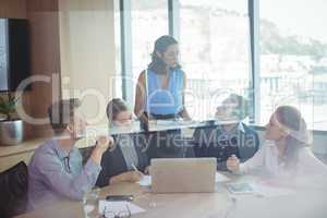 Business partners discussing in meeting seen through glass