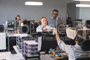 Businessman giving document to colleague working at office