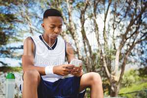 Teenage boy using smart phone while sitting on bench