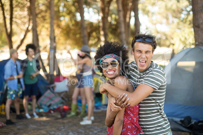 Portrait of cheerful friends embracing at campsite