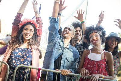 Happy friends with arms raised enjoying during music festival