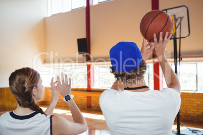 Rear view of coach training basketball player in court