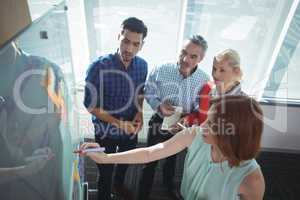 High angle view of businesswoman explaining to colleagues over whiteboard