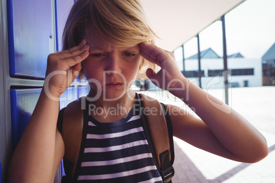 Boy suffering from headache while standing by lockers