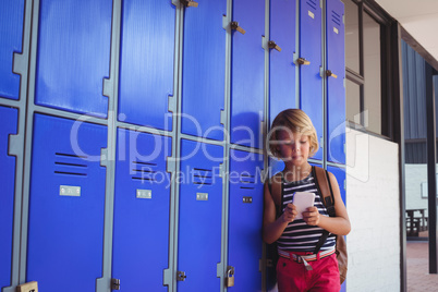 Schoolboy using mobile phone while standing by lockers