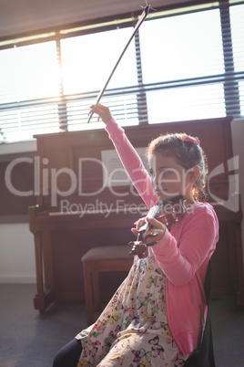 Cute girl rehearsing violin in music class