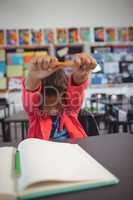Schoolgirl stretching hands while sitting at desk
