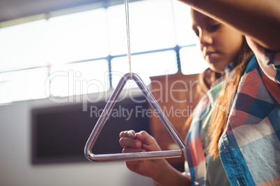Low angle view of girl playing triangle