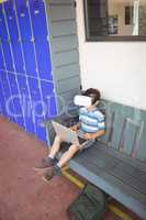 Boy using laptop and virtual reality glasses while sitting on bench