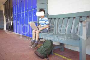 Full length of boy using laptop and virtual reality glasses while sitting on bench