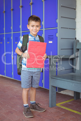 Portrait of happy boy holding books in corridor