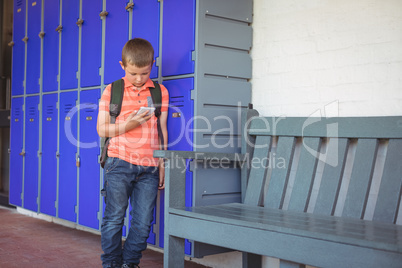Boy using mobile phone while leaning on lockers