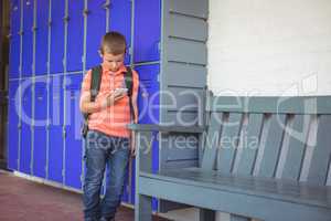 Boy using mobile phone while leaning on lockers