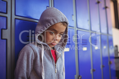 Thoughtful boy making face by lockers