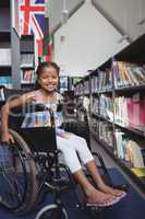Smiling girl sitting on wheelchair in library