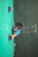 Boy reaching climbing holds on green wall