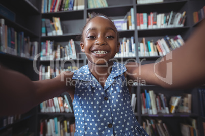 Happy girl against bookshelf in library