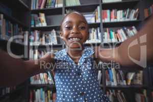 Happy girl against bookshelf in library