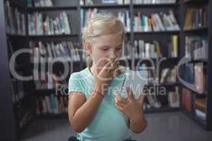 Surprised girl looking at smartphone in library