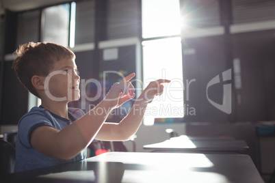 Smiling boy gesturing while sitting at desk