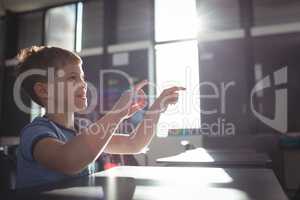 Smiling boy gesturing while sitting at desk