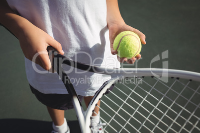 Midsection of girl holding tennis racket and ball