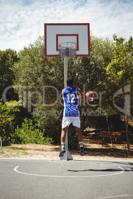 Teenage basketball player scoring while practicing at court