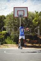Teenage basketball player scoring while practicing at court