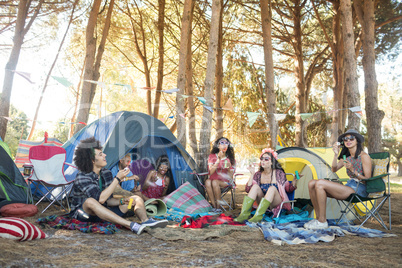 Young friends sitting together at campsite