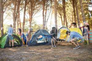 Young friends setting up their tents together on field