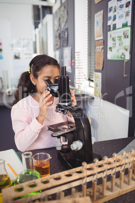 Elementary student looking through microscope at laboratory