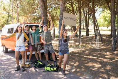 Happy friends hitchhiking on road