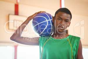 Portrait of confident teenage boy holding basketball