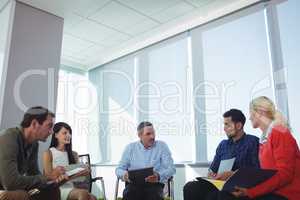 Business people discussing while sitting by window at office