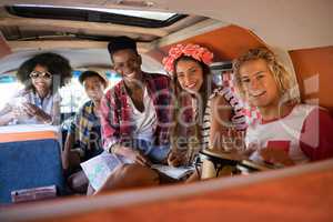 Portrait of smiling friends sitting in camper van
