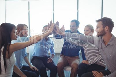 Business colleagues putting their hands together in office