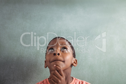 Thoughtful boy against greenboard in classroom