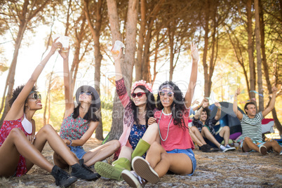 Cheerful friends with arm raised at campsite