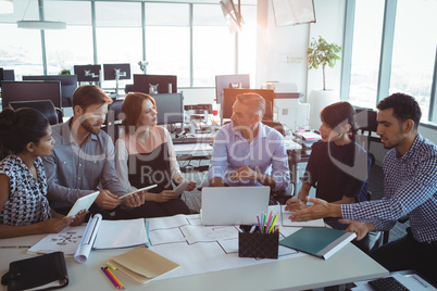 High angle view of creative business colleagues discussing around desk