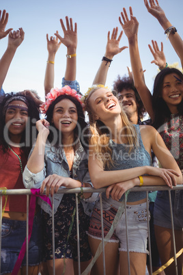 Happy female friends standing by railing at music festival