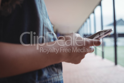 Mid section of girl using mobile phone in corridor