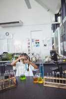 Elementary student doing experiment with blue chemical at laboratory