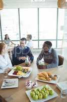 Smiling business colleagues having breakfast at office cafeteria