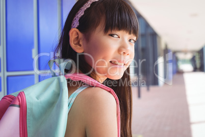 Portrait of smiling girl with backpack in corridor